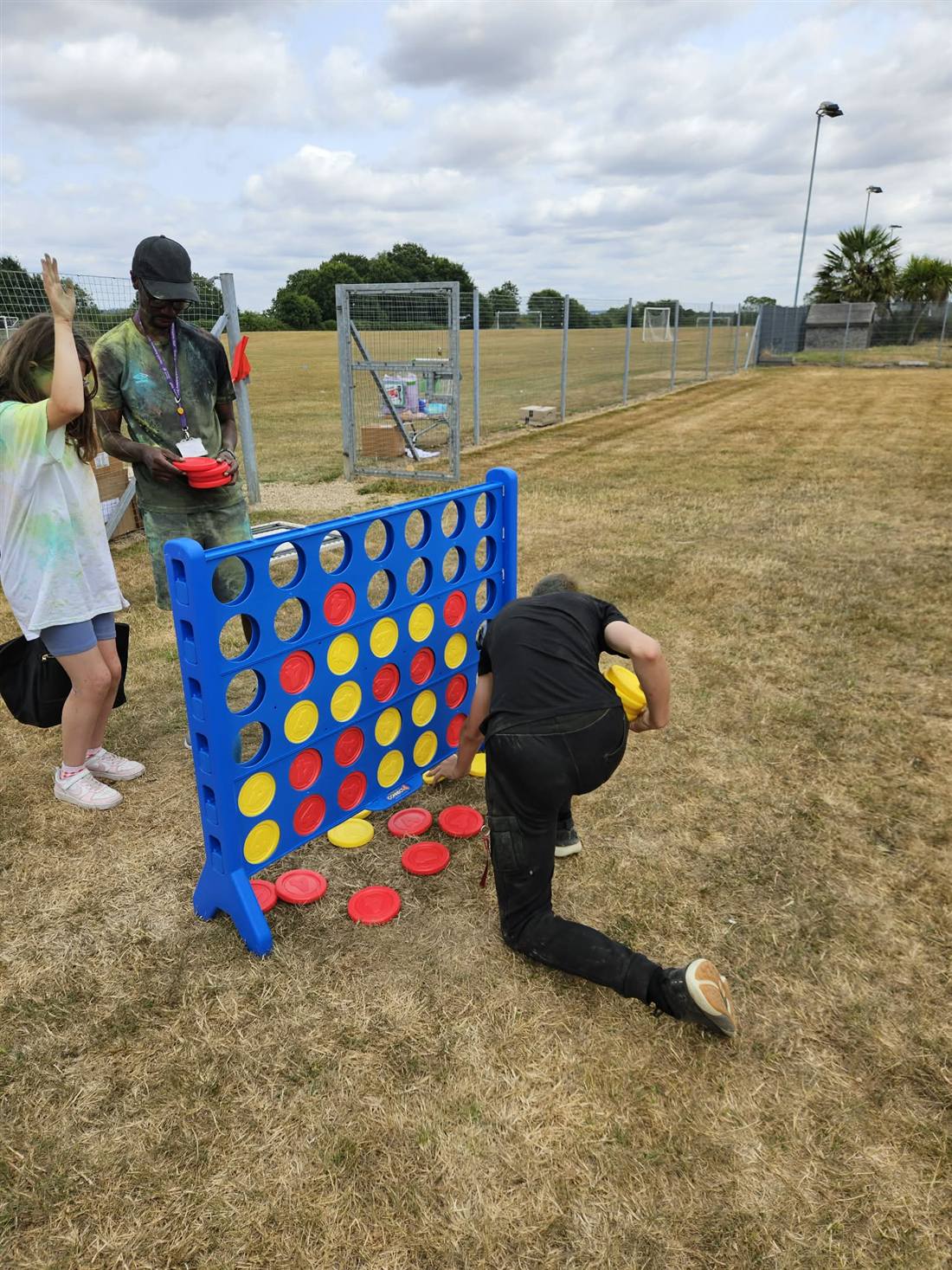 Paint-covered players mid-game at giant Connect Four during a school colour run
